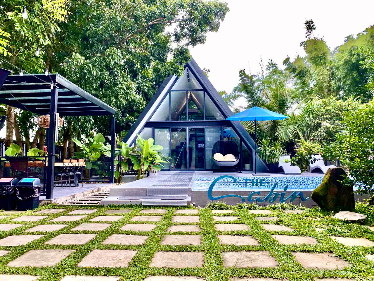 A-frame glass cabin at Oliva's Resort surrounded by tropical greenery